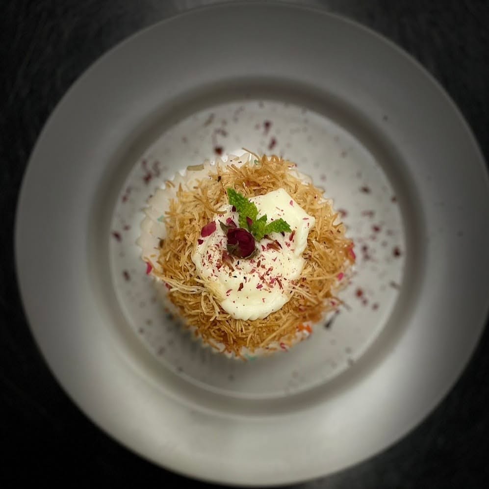 Individual kunafa topped with cream, dried rose petals and mint