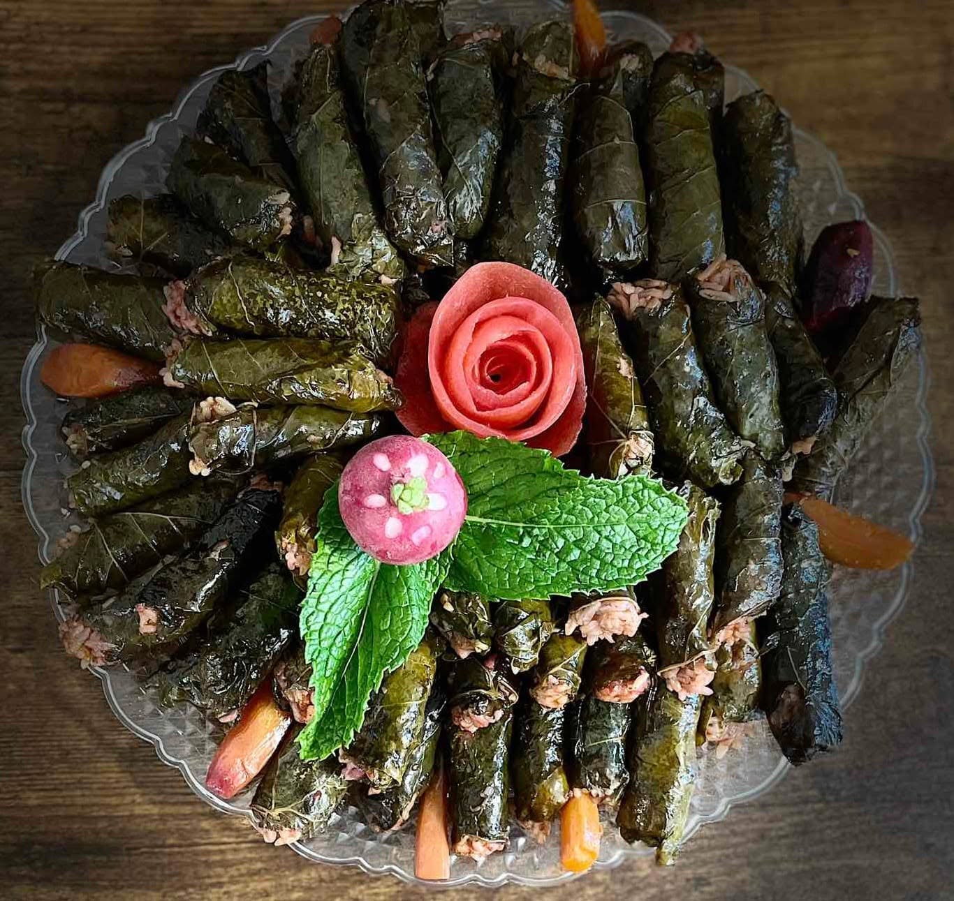 Round platter of grape leaf dolma and iprax with carrots and mint